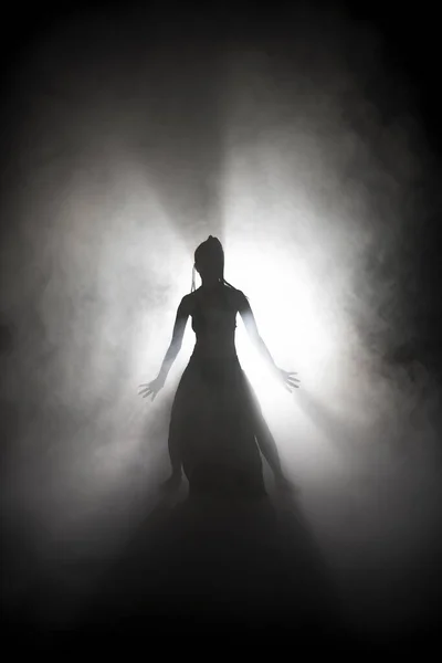 Silhouette dancer woman performing dance figures in fog. — Stock Photo, Image