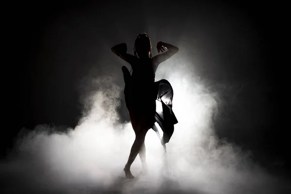 Silhouette χορεύτρια γυναίκα εκτελεί χορευτικές φιγούρες στην ομίχλη. — Φωτογραφία Αρχείου