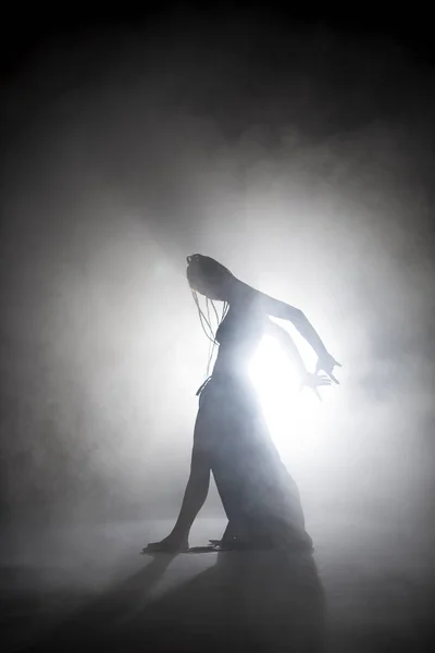 Silhouette dancer woman performing dance figures in fog. — Stock Photo, Image