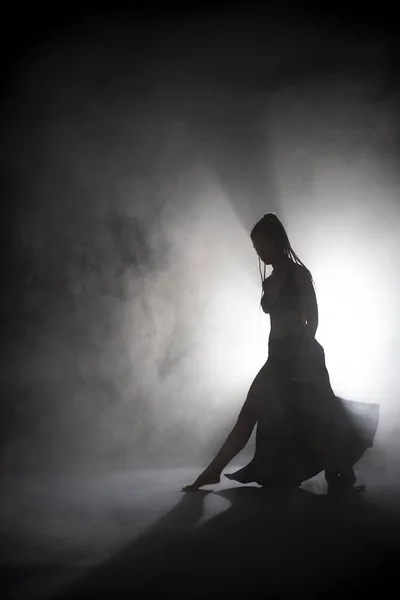 Silueta bailarina mujer realizando figuras de baile en la niebla . — Foto de Stock