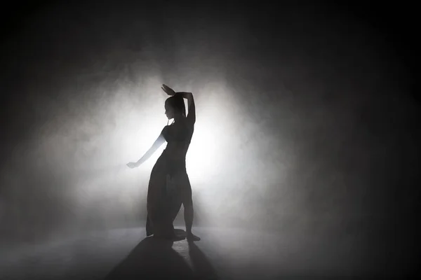 Dançarina silhueta executando figuras de dança no nevoeiro . — Fotografia de Stock