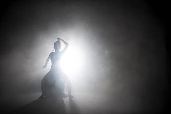 Sylwetka tancerka kobieta wykonywania postaci tanecznych we mgle. — Zdjęcie stockowe