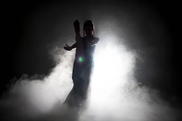 Silhouette dancer woman performing dance figures in fog. — Stock Photo, Image