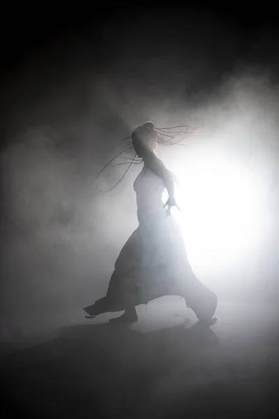 Silueta bailarina mujer realizando figuras de baile en la niebla . — Foto de Stock