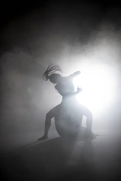 Silhueta dançarina mulher realizando figuras de dança no nevoeiro . — Fotografia de Stock