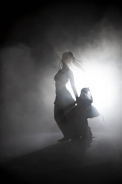 Silhouette χορεύτρια γυναίκα εκτελεί χορευτικές φιγούρες στην ομίχλη. — Φωτογραφία Αρχείου