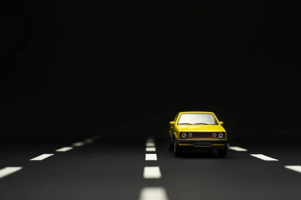 Vista frontal de um carro de brinquedo sedan amarelo com duas portas em um b preto — Fotografia de Stock