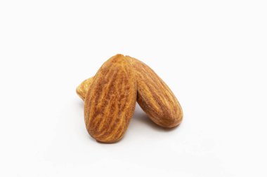Beyaz arka planda üç kavrulmuş badem yakın çekim.