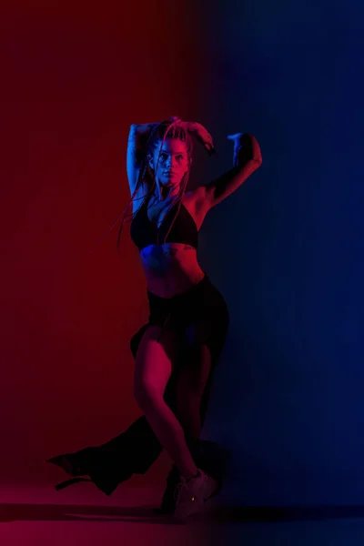 Negro vestido y trenzado mujer de pelo bailando en un azul y rojo b —  Fotos de Stock