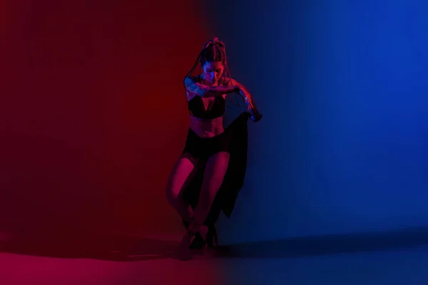 Чорне вбрання і плетене волосся жінка танцює на синьому і червоному б — стокове фото