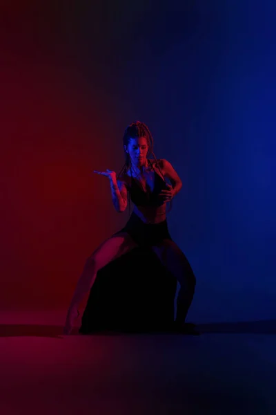 Siyah giyimli ve örgülü saçlı kadın mavi ve kırmızı bir B 'de dans ediyor. — Stok fotoğraf
