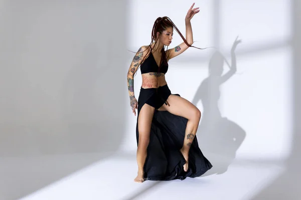 Negro vestido y trenzado mujer de pelo con tatuajes bailando en una w —  Fotos de Stock