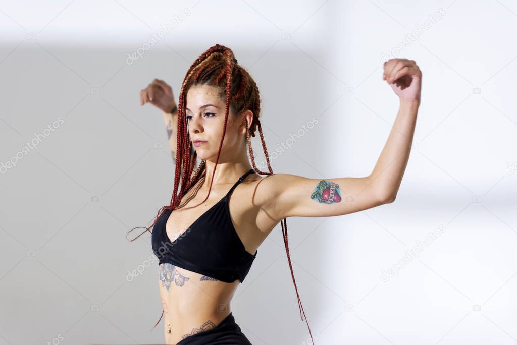 Black dressed and braided hair woman with tattoos dancing on a w
