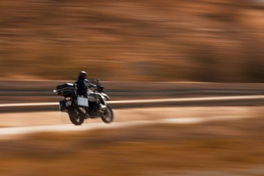 Siyah renkli motosiklet pozu, hareket bulanıklığı olan pan tekniğiyle..