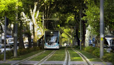 İzmir Tramvayı ağaçların ve yeşil çimlerin arasında.