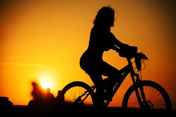 Silueta mujer montando una bicicleta en la puesta del sol . —  Fotos de Stock