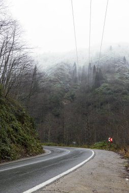 Tepelerin arasında kıvrılan ıslak yol.