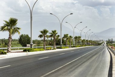 Straight road background with cloudy sky.