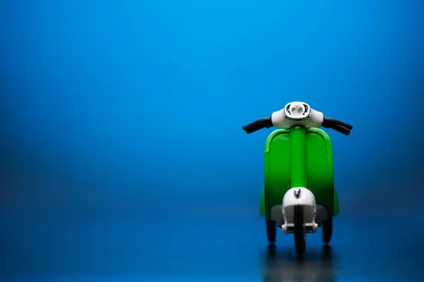 Zielony kolorowy skuter na niebieskim tle. — Zdjęcie stockowe