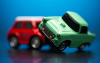 Mavi arka planda kırmızı ve yeşil oyuncak arabalar arasındaki trafik kazasını yakından çek..