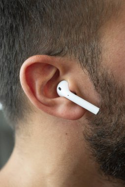Izmir, Turkey - July  12, 2019: Close up shot of the one of Apple brand airpods on a caucasian white males ear.