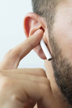 Izmir, Turkey - July  12, 2019: Close up shot of the one of Apple brand airpods on a caucasian white males ear and pushing it with forefinger.