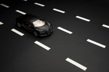 İzmir, Türkiye - 28 Temmuz 2019: Siyah arka plan ve karayolları üzerindeki Siyah Bugatti Veyron Oyuncak arabasının ön ve üst görüntüsü.
