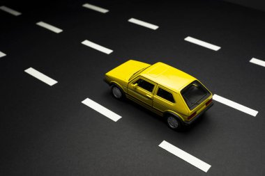 İzmir, Türkiye - 28 Temmuz 2019: Yol şeritli asfalt bir yolda üst ve arka manzaralı sarı oyuncak araba 