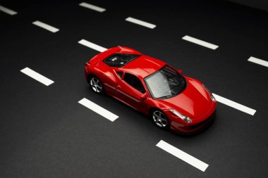 İzmir, Türkiye - 28 Temmuz 2019: Yol şeritli asfalt bir yolda kırmızı oyuncak spor arabanın üst ve ön manzarası.