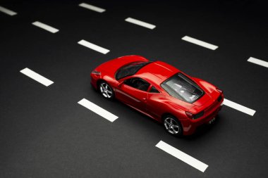 İzmir, Türkiye - 28 Temmuz 2019: Yol şeritli asfalt bir yolda kırmızı oyuncak spor arabanın üst ve arka manzarası.