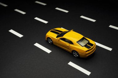 İzmir, Türkiye - 28 Temmuz 2019: Yol şeritli asfalt bir yolda iki kapılı ve siyah çizgili bir Chevrolet Camaro Sarı spor arabanın üst ve arka manzarası.