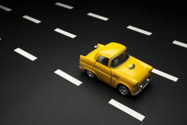 İzmir, Türkiye - 28 Temmuz 2019: Yol şeritli asfalt bir yolda sarı renkli 50 'li yılların oyuncak arabasının ön ve üst görüntüsü.