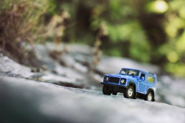 İzmir, Türkiye - 28 Temmuz 2019: Kayalıklarda eski moda bir tarz olan Mavi SUv ön tarafta ve yeşil arka planda poz veriyor.