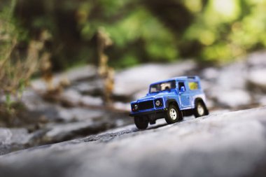 İzmir, Türkiye - 28 Temmuz 2019: Kayalıklarda eski moda bir tarz olan Mavi SUv ön tarafta ve yeşil arka planda poz veriyor.