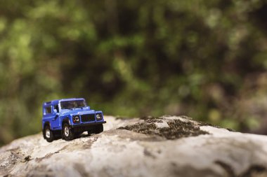 İzmir, Türkiye - 28 Temmuz 2019: Kayalıklarda eski moda bir tarz olan Mavi SUv ön tarafta ve yeşil arka planda poz veriyor.