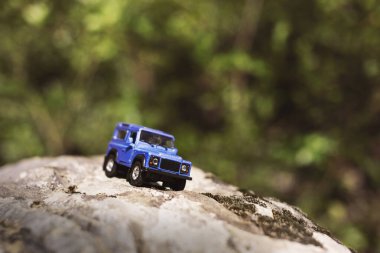 İzmir, Türkiye - 28 Temmuz 2019: Kayalıklarda eski moda bir tarz olan Mavi SUv ön tarafta ve yeşil arka planda poz veriyor.