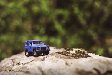 İzmir, Türkiye - 28 Temmuz 2019: Kayalıklarda eski moda bir tarz olan Mavi SUv ön tarafta ve yeşil arka planda poz veriyor.