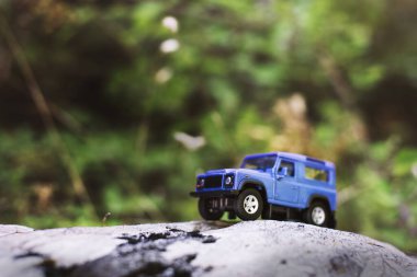 İzmir, Türkiye - 28 Temmuz 2019: Kayalıklarda eski moda bir tarz olan Mavi SUv ön tarafta ve yeşil arka planda poz veriyor.