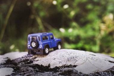 İzmir, Türkiye - 28 Temmuz 2019: Kayalıklarda, arka tarafta ve yeşil arka planda eski moda bir model olan Mavi SUv.