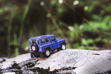 İzmir, Türkiye - 28 Temmuz 2019: Kayalıklarda, arka tarafta ve yeşil arka planda eski moda bir model olan Mavi SUv.