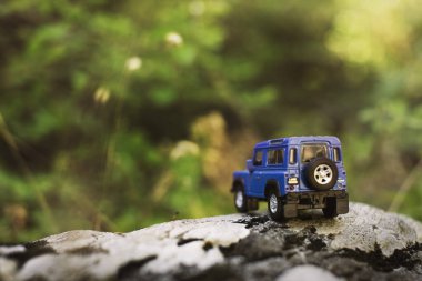 İzmir, Türkiye - 28 Temmuz 2019: Kayalıklarda, arka tarafta ve yeşil arka planda eski moda bir model olan Mavi SUv.