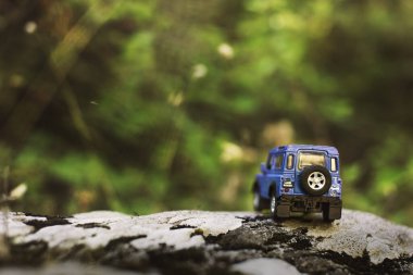 İzmir, Türkiye - 28 Temmuz 2019: Kayalıklarda, arka tarafta ve yeşil arka planda eski moda bir model olan Mavi SUv.
