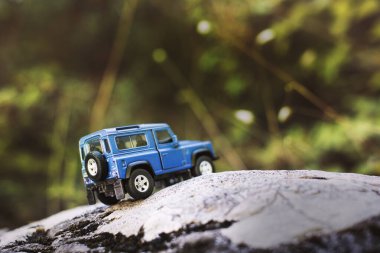 İzmir, Türkiye - 28 Temmuz 2019: Kayalıklarda, arka tarafta ve yeşil arka planda eski moda bir model olan Mavi SUv.