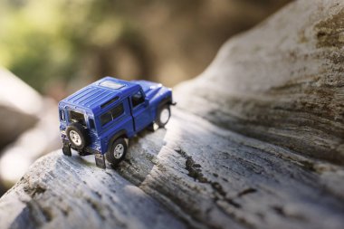 İzmir, Türkiye - 28 Temmuz 2019: Kayalıklarda, arka tarafta ve yeşil arka planda eski moda bir model olan Mavi SUv.