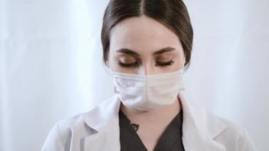 Beyaz bir arka planda maske ve eldiven takan bir kadın doktorun portresi..