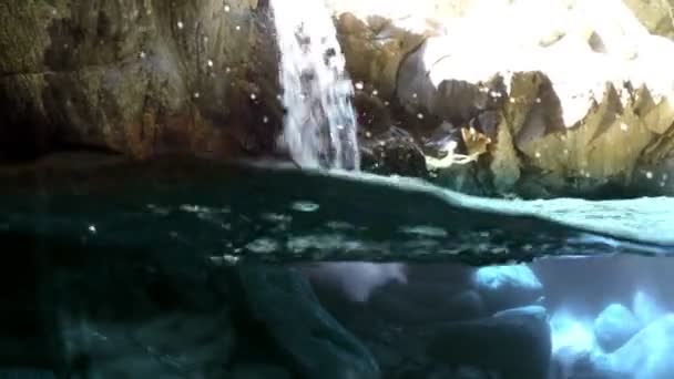 Petite vue cascade depuis la moitié sous l'eau entre les rochers et avec quelques poissons .