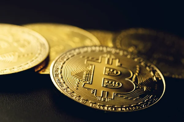Yüksek kontrastlı siyah arkaplandaki altın renkli bitcoin paralar.