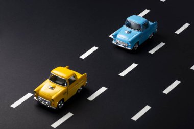 Yolda peş peşe iki oyuncak araba. Biri mavi, diğeri sarı renkli. Görüntü trafikte takip edilen mesafeyi anlatıyor.