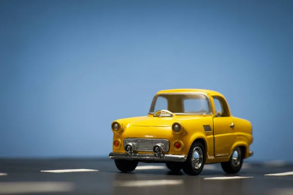 Widok Przodu Żółtego Samochodu Zabawki Niebieskim Tle Drodze Asfaltowej — Zdjęcie stockowe