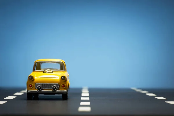 Vista Frontal Carro Brinquedo Amarelo Fundo Azul Uma Estrada Asfalto — Fotografia de Stock